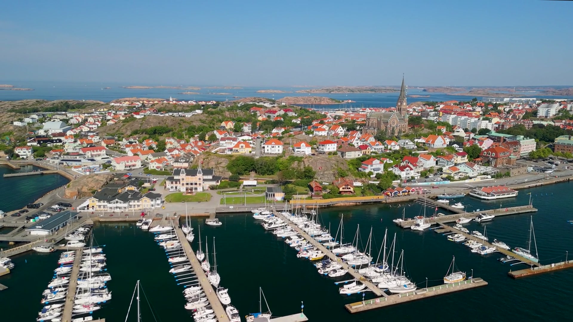 Drönarbild över Lysekils gästhamn med segelbåtar, staden och kyrkan i bakgrunden.